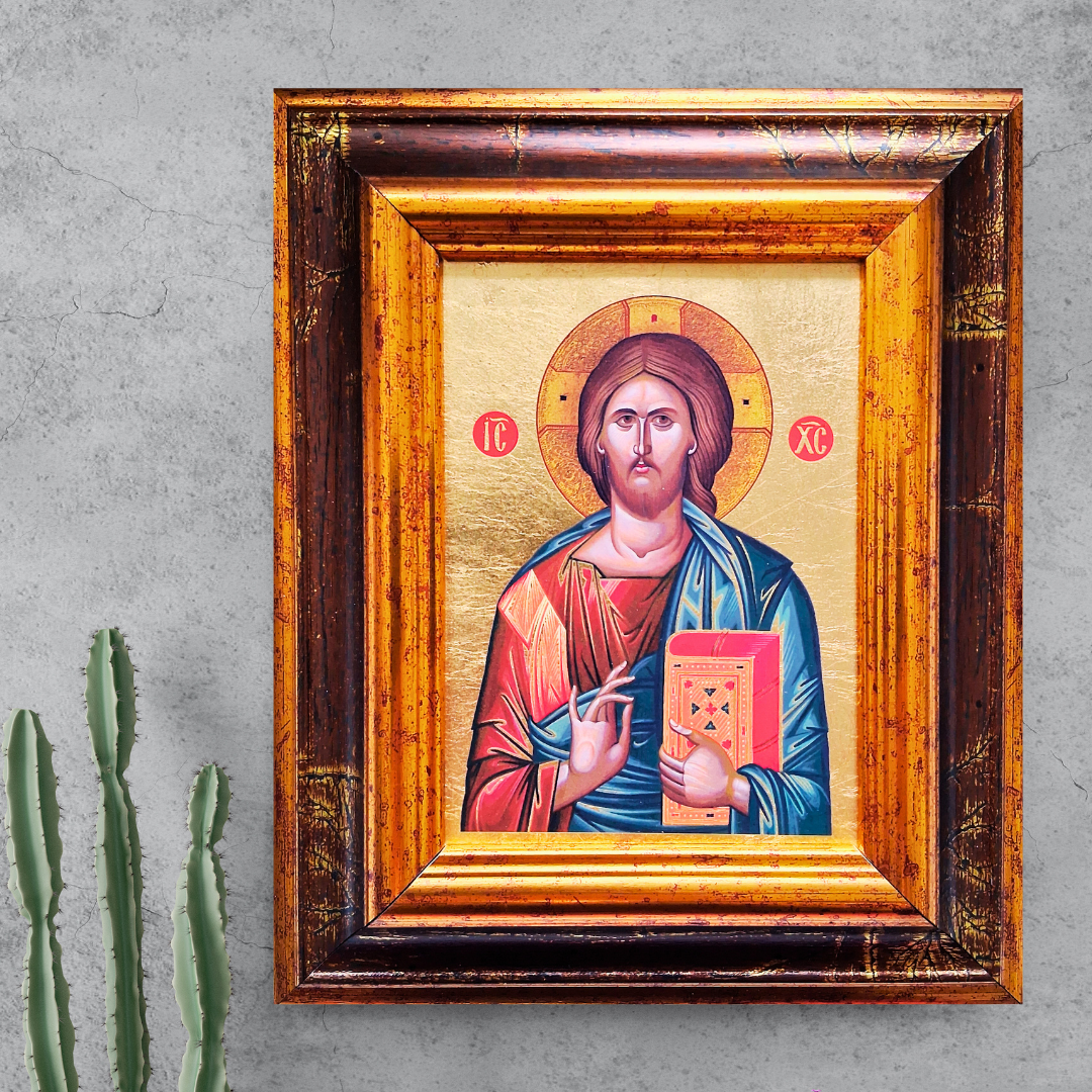 Ikone Christus Pantokrator im verzierten Holzrahmen vor grauer Wand mit Kaktuspflanze.