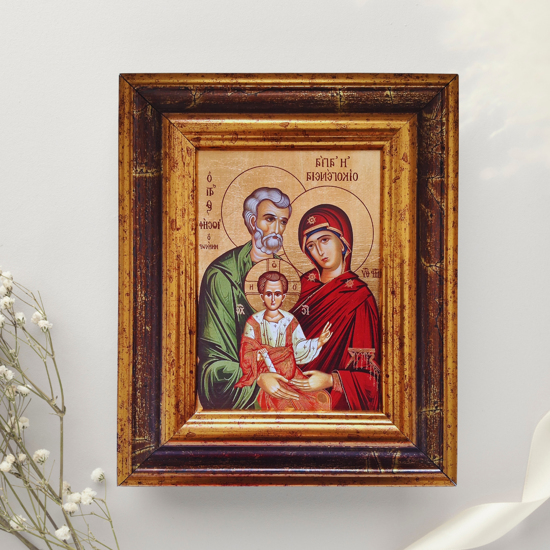 Ikone „Die Heilige Familie“ im verzierten Holzrahmen vor weißem Hintergrund mit Dekozweig.