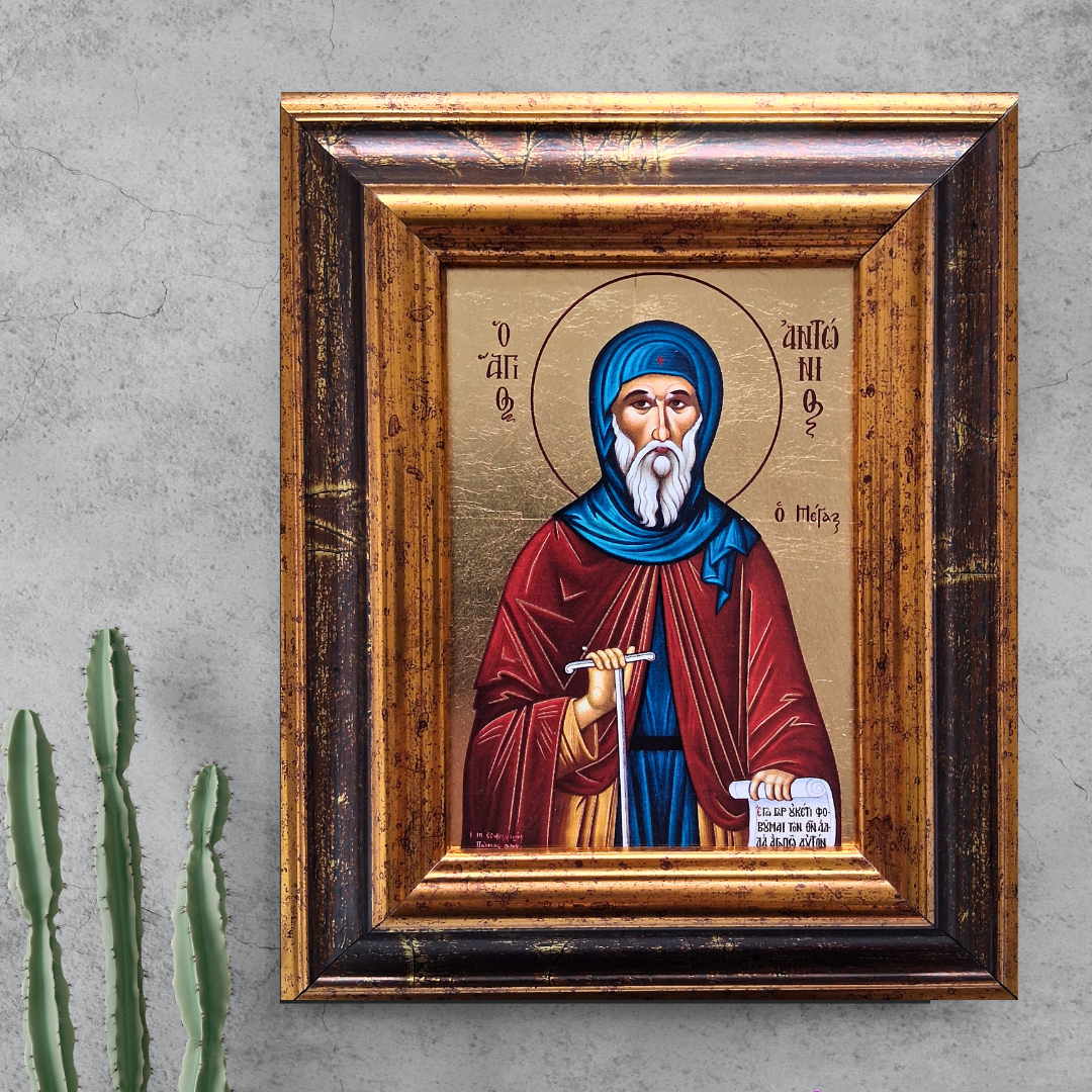 Ikone des Heiligen Antonius im verzierten Holzrahmen vor grauer Wand mit Kaktuspflanze.