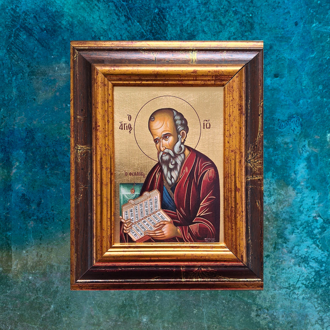 Ikone des Heiligen Johannes des Theologen im verzierten Holzrahmen vor blau-grünem Hintergrund.