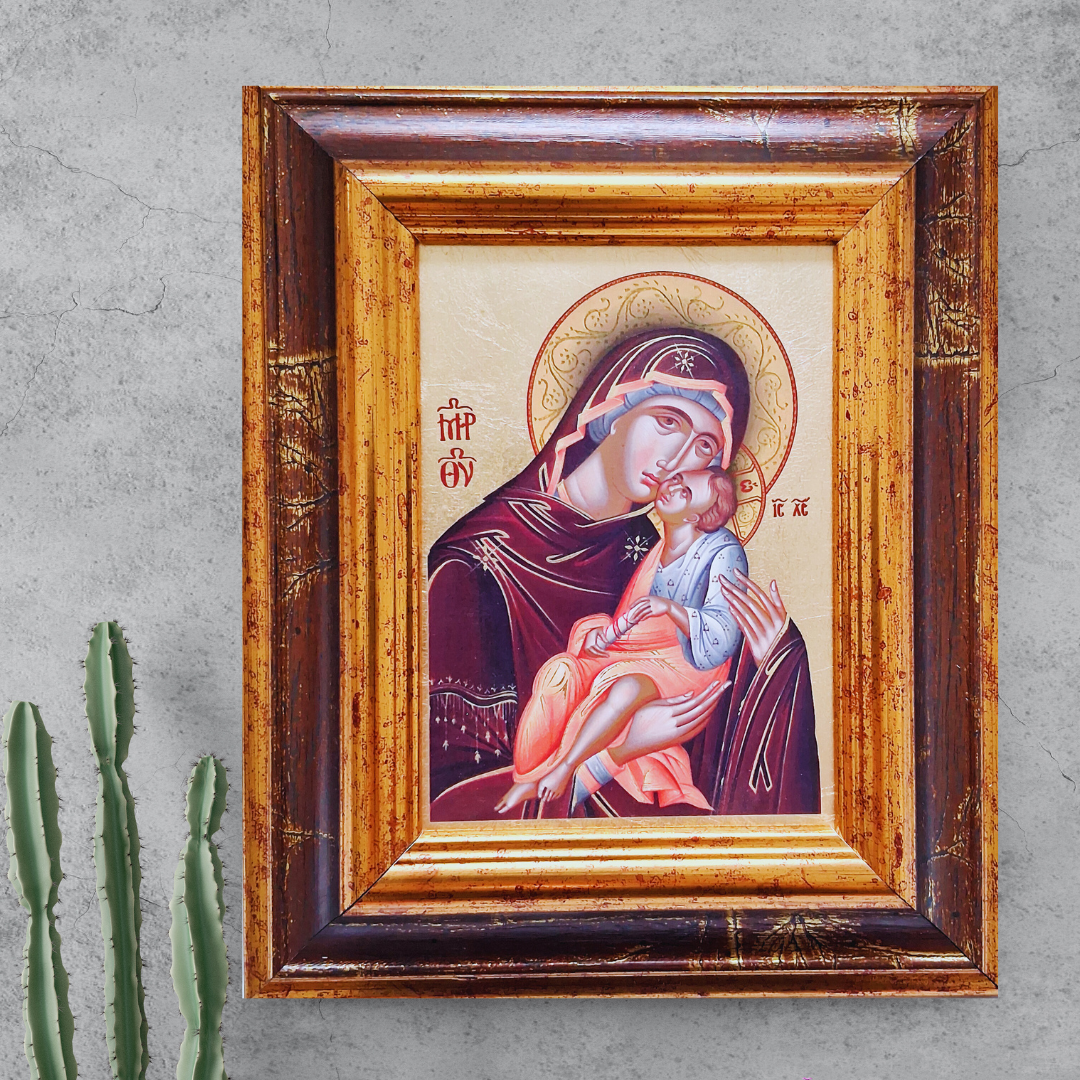 Ikone „Madonna Glikofilussa“ im verzierten Holzrahmen vor grauer Wand mit Kaktuspflanze.